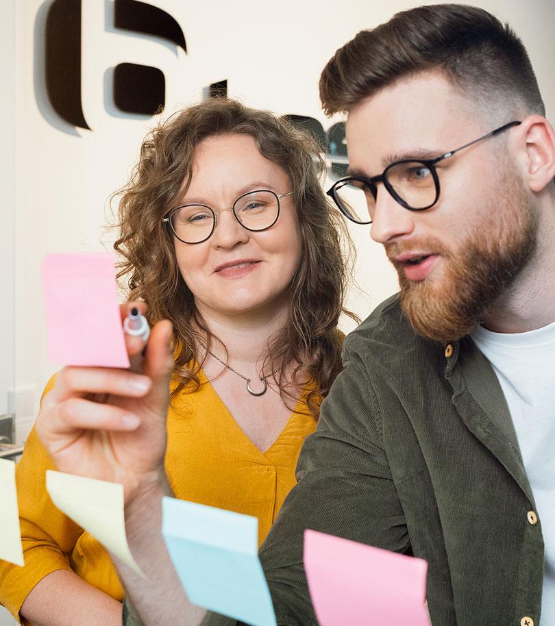 zwei MitarbeiterInnen ordnen Zettel an der Flipchart